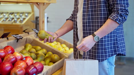 man shopping for pears and apples in a grocery store