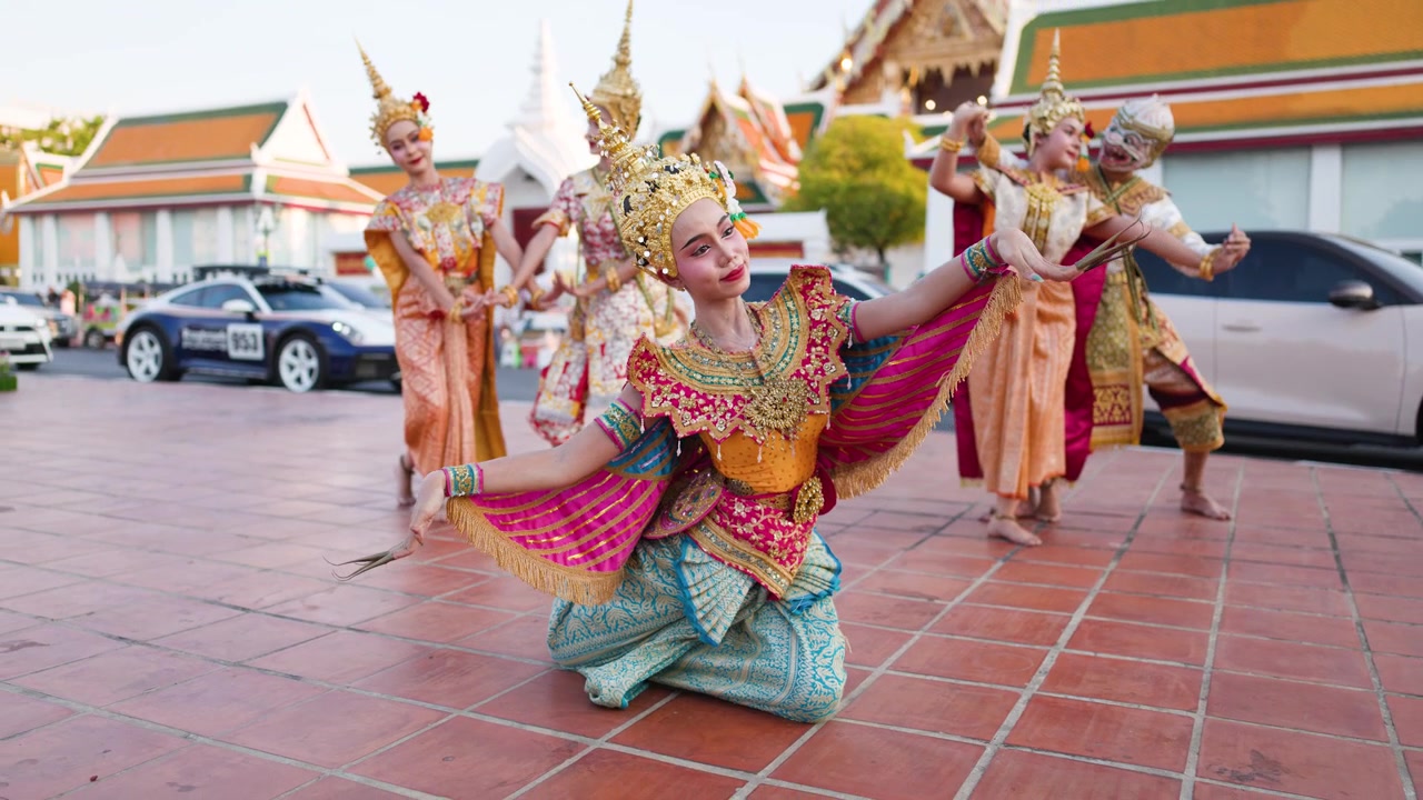 Penari dengan kostum emas berornamen menampilkan gerakan Khon tradisional di luar kuil bersejarah Bangkok