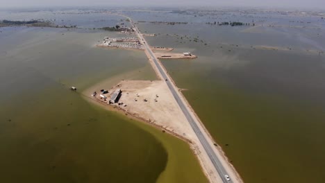 vista aérea de una carretera elevada solitaria rodeada de aguas de inundación expansivas en la zona rural de jacobabad, sindh