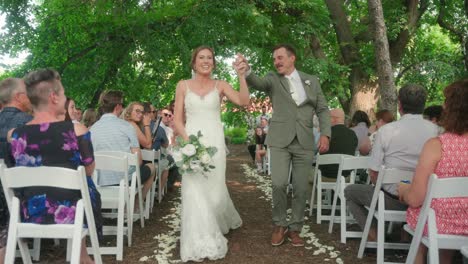bride and groom walk down aisle after getting married groom dips bride for kiss