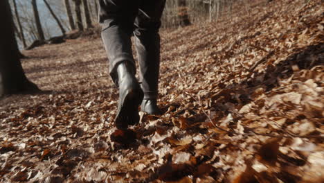 Hombre-Con-Botas-Caminando-En-El-Suelo-Del-Bosque-Con-Muchas-Hojas-Girando-Alrededor