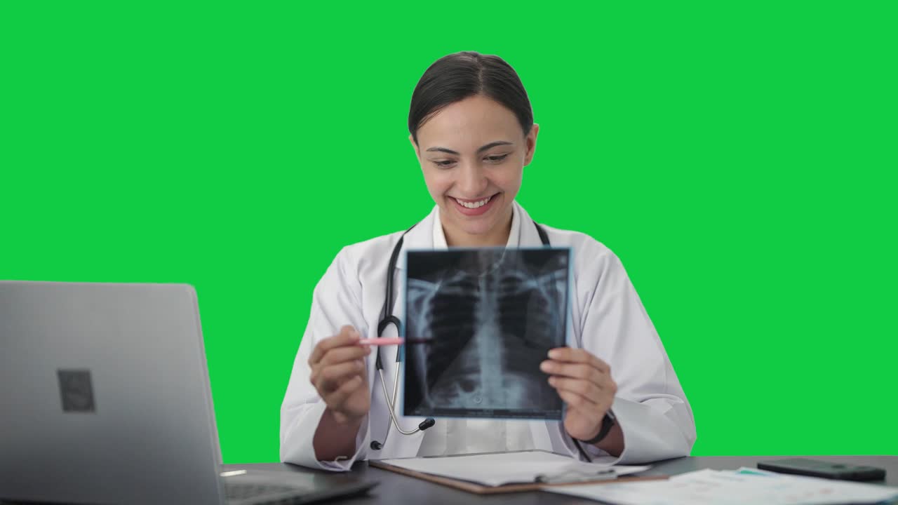 Happy Indian female doctor checking X ray test Green screen