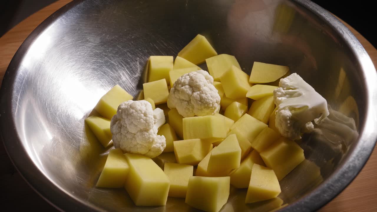 el chef está agregando verduras al tazón de metal, cocinando pollo frito y verduras asadas