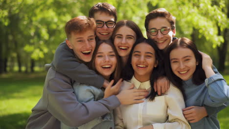 group of happy young friends hugging in a park