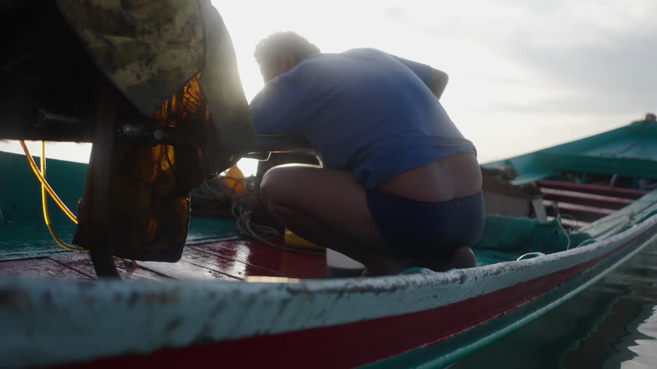 Persona trabajando en un barco tradicional al amanecer o al atardecer