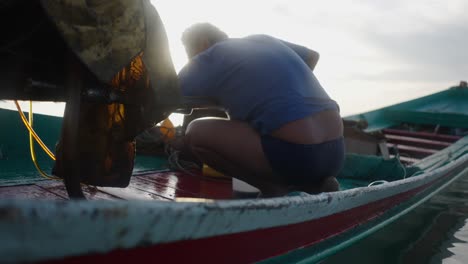 person working on a traditional boat at sunrise or sunset