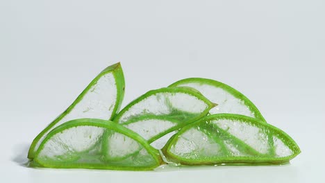 el gel de extracto transparente fluye a través del aloe vera cortado en rodajas sobre un fondo blanco. planta médica natural para cosméticos orgánicos, medicina alternativa