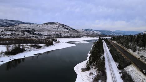 the thompson river and highway 1, with wintery mountains in kamloops, british columbia