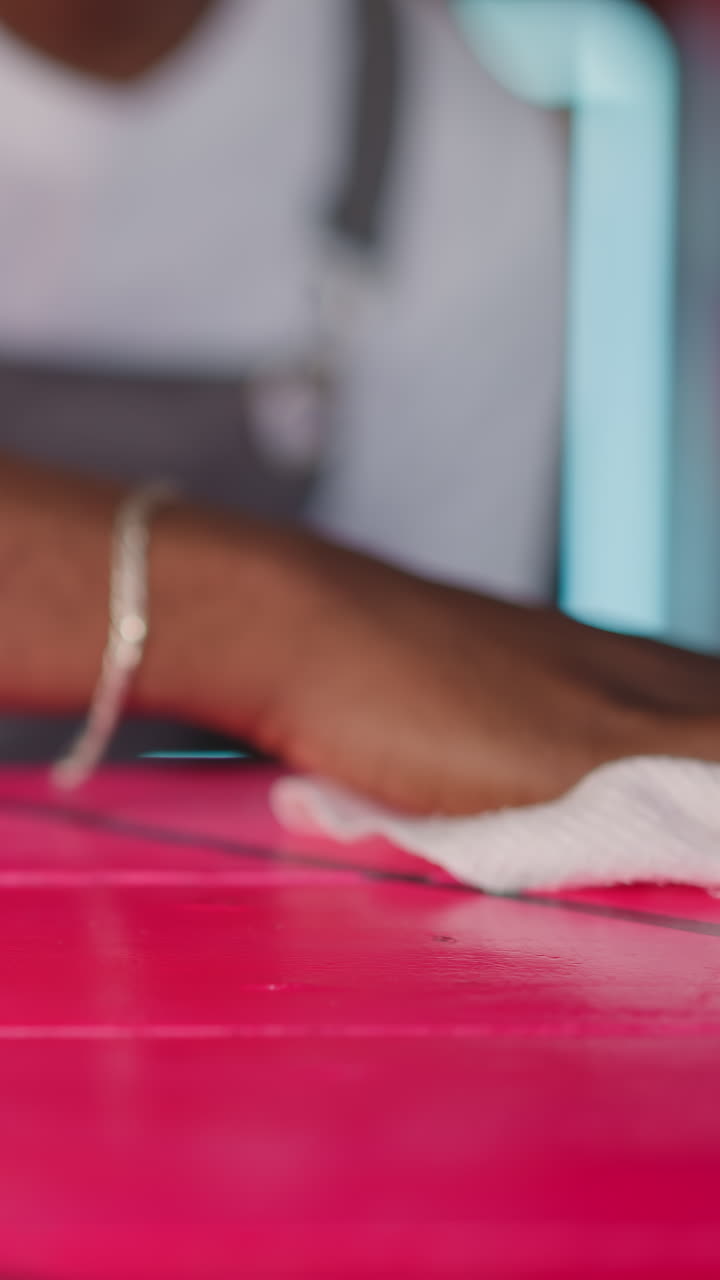 Barman cleans counter in club closeup. Black waiter wipes colorful countertop in bar. African American bartender removes dirt from desk in cafe