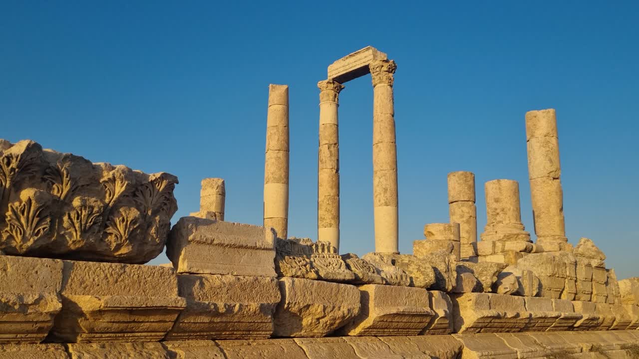 Il sole del tardo pomeriggio illumina le rovine del Tempio di Ercole sulla collina della Cittadella di Amman, in Giordania, mettendo in risalto pietre antiche e architettura storica in una pacifica atmosfera dell'ora d'oro.