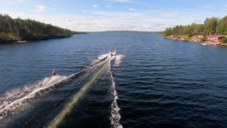 slowmotion of drone flying over a young man riding a wakeboard after a sport boat in the swedish archipelago in the summer sub3