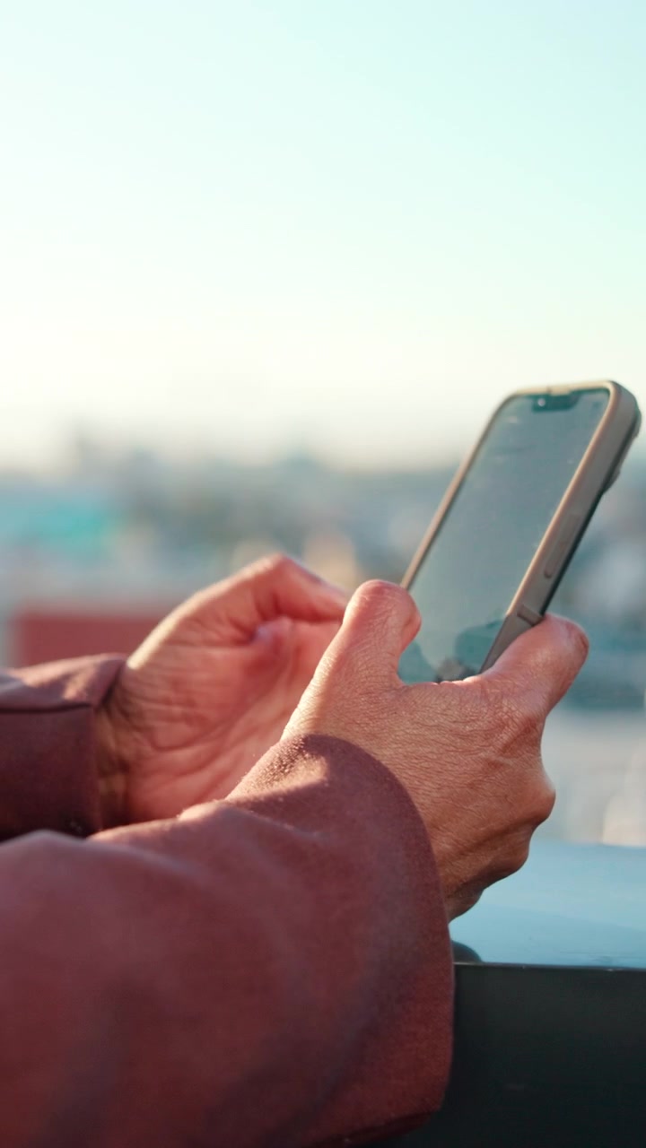 Persona che usa lo smartphone all'aperto al tramonto.