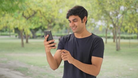 Happy-Indian-man-using-phone-in-park