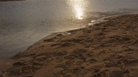 Inclinación-Desde-Huellas-En-La-Arena-Hasta-Puesta-De-Sol-Sobre-El-Agua