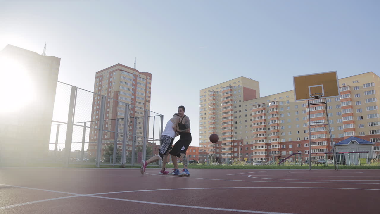 Two Men Playing Basketball on an Outdoor Court