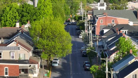 A-slow-ascending-shot-looking-down-a-street-lined-with-power-lines-from-the-power-grid-with-cars-parked-and-driving-down-the-street-in-the-USA