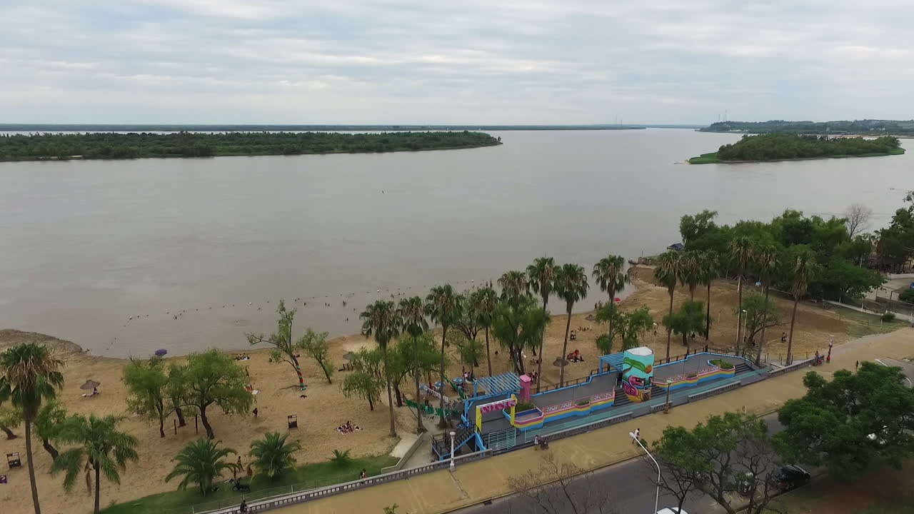 vista aérea del río de la ciudad de paraná y el tráfico en la carretera costera bajo el parque urquiza, islas en verde exuberante en un día nublado de verano, argentina