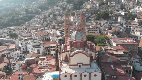 back aerial view of the catedral of tasco in mexico, showing the beautiful design of its dome and the size of the building caompare to the surrounding house´s