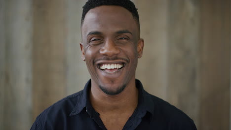 portrait of lively young african american man laughing excited enjoying successful lifestyle wearing black shirt slow motion