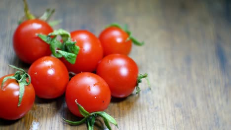 tomates cherry mojados jugosos rojos diminutos frescos crudos en el enfoque selectivo de la superficie de la cocina de madera
