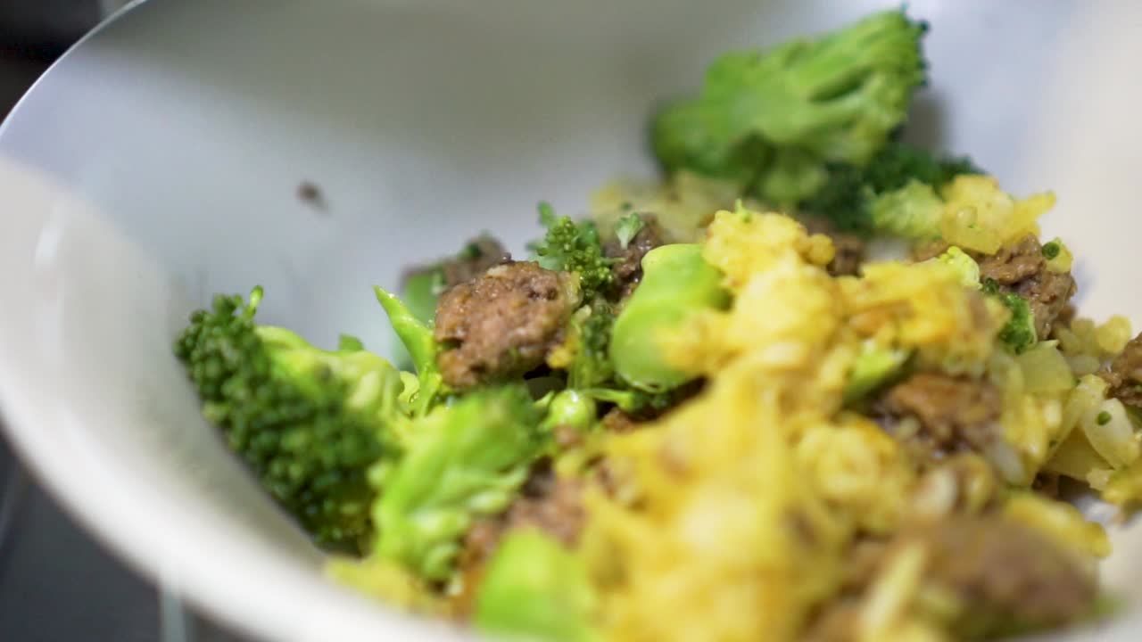 SLOWMO - Putting food curry rice with broccoli and beef mince meat in bowl to serve