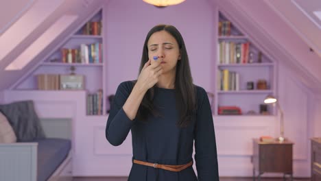una chica india enferma midiendo la fiebre con un termómetro.