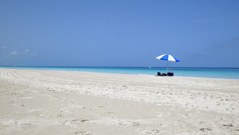 Impresionante-Playa-De-Varadero-Durante-Un-Día-Soleado,-Arena-Blanca-Y-Fina-Y-Mar-Caribe-Turquesa-Y-Verde,-A-La-Derecha-Una-Sombrilla-Azul,-Cuba