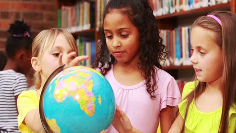 little girls looking at globe in library