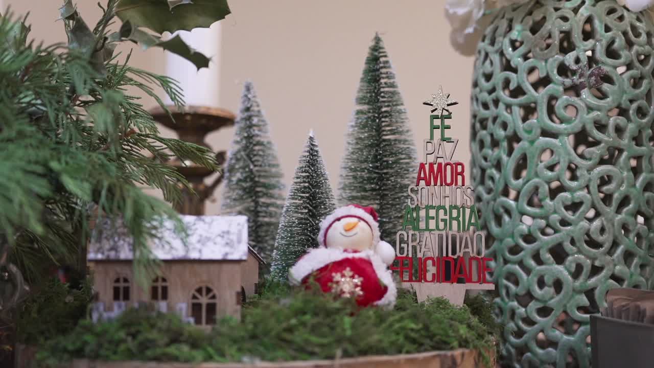 Miniature christmas village scene with snowman, trees, and festive message sign
