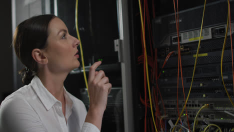 Caucasian-female-it-technician-pointing-and-checking-computer-server