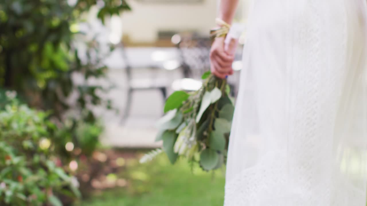 mujer caucásica sosteniendo un ramo de flores en el jardín en un día soleado