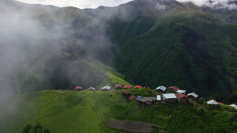 wide revealing cinematic rotating drone shot through the clouds of a small village on a mountain top in tusheti village in georgia