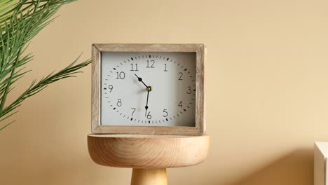 stylish wooden square clock on wooden stand with plant