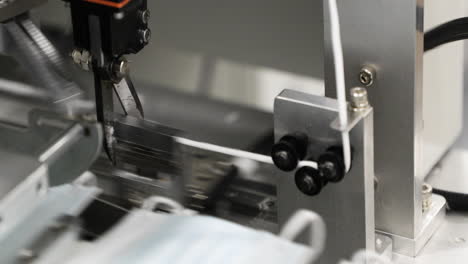 máquina de fábrica moderna con tijera de corte automático para elástico - fabricante de máscara desechable - primer plano
