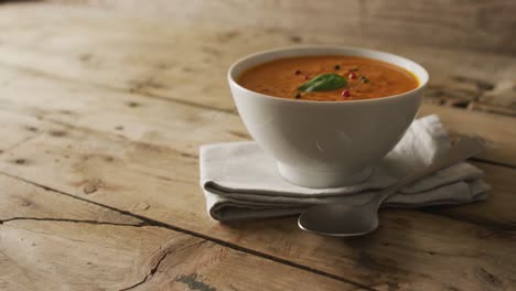 video of cream tomato soup in bowl on wooden table with cutlery