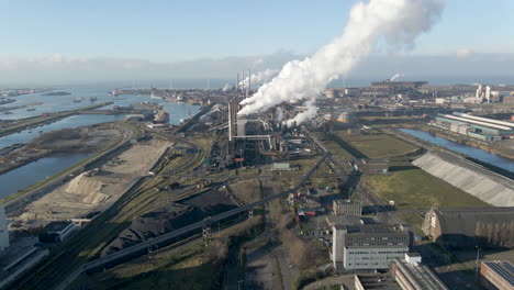 flying up to large steel mill with smoking chimneys