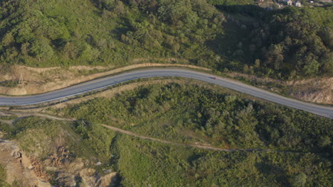 Car-moving-on-a-mountain-road-with-green-forest-on-the-sides,-on-the-sunset,-Russia,-Far-East