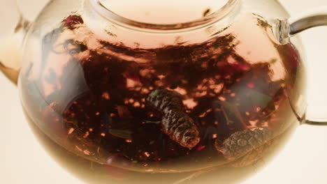 glass teapot with pine cone and berry infused tea