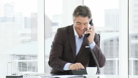 happy businessman talking on phone in office