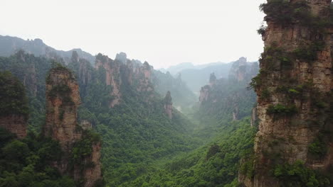 Surreal-nature-aerial:-misty-jungle-valley-amid-tall-rocky-spires