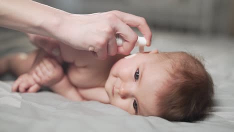primer plano de un niño pequeño, las manos de la madre usan spray para los oídos del bebé