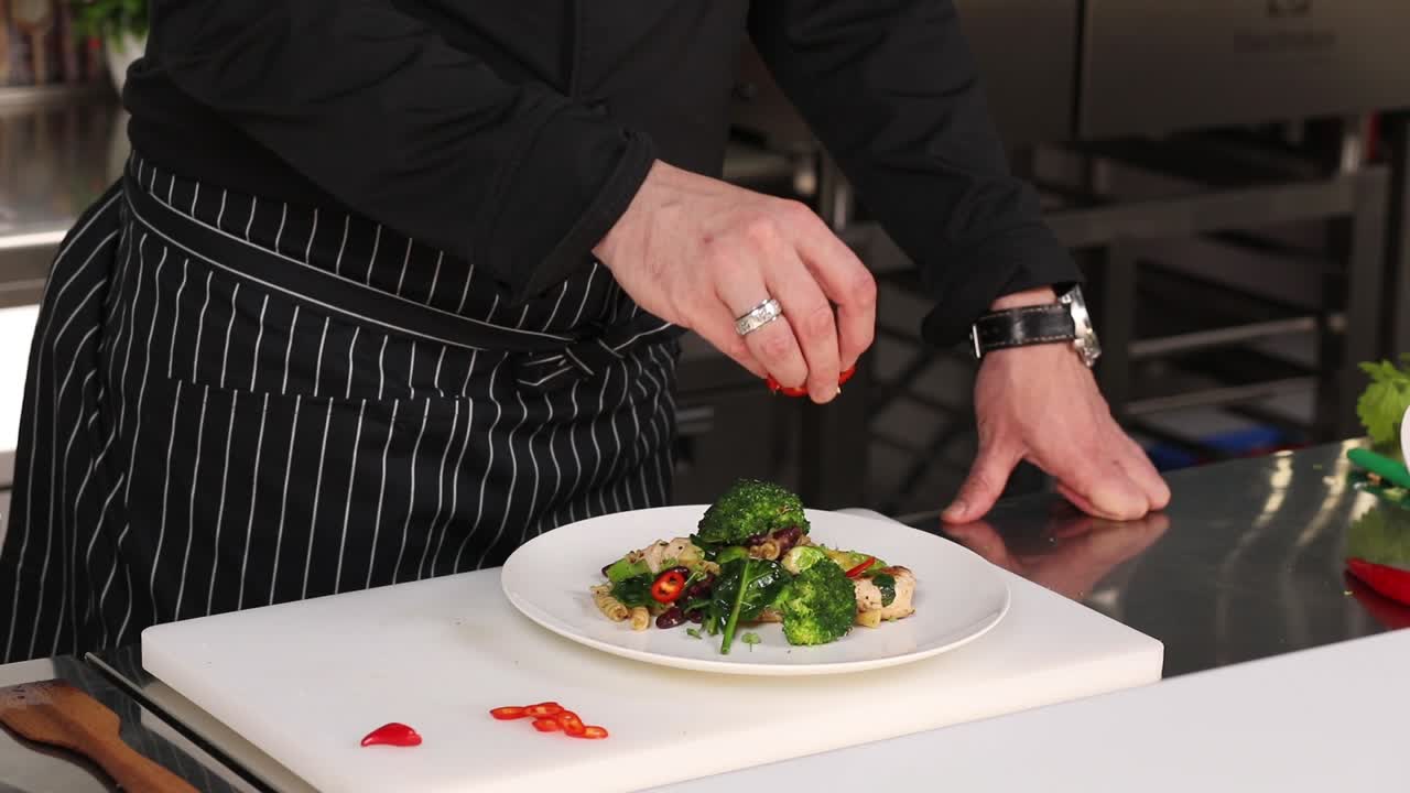 Chef Seasoning a Plate of Pasta with Vegetables