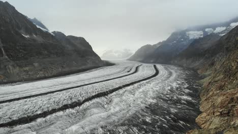 aerial flyover alongside the longest glacier in the alps - the aletsch glacier in valais, switzerland - with view of jungfrau in the clouds