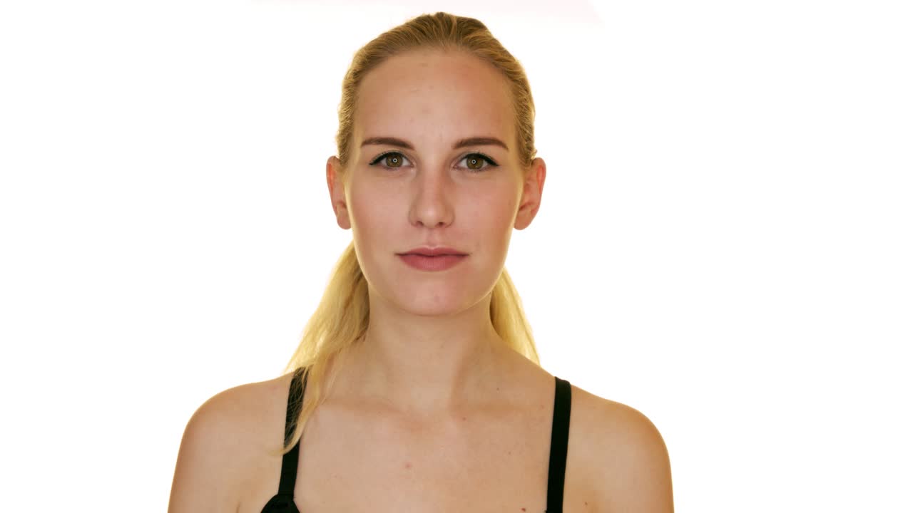 молодая женщина в лифчике смеется в камеру и закрывает глаза