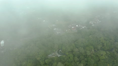 a aerial view with the camera peering down through fog to reveal a lush landscape below