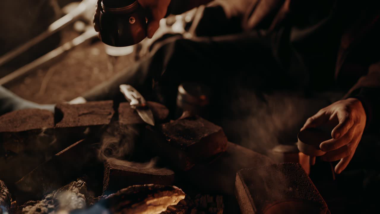 café de la fogata: joven vertiendo el exceso de agua del compartimento de su olla de moka sobre los ladrillos calientes de su fogata