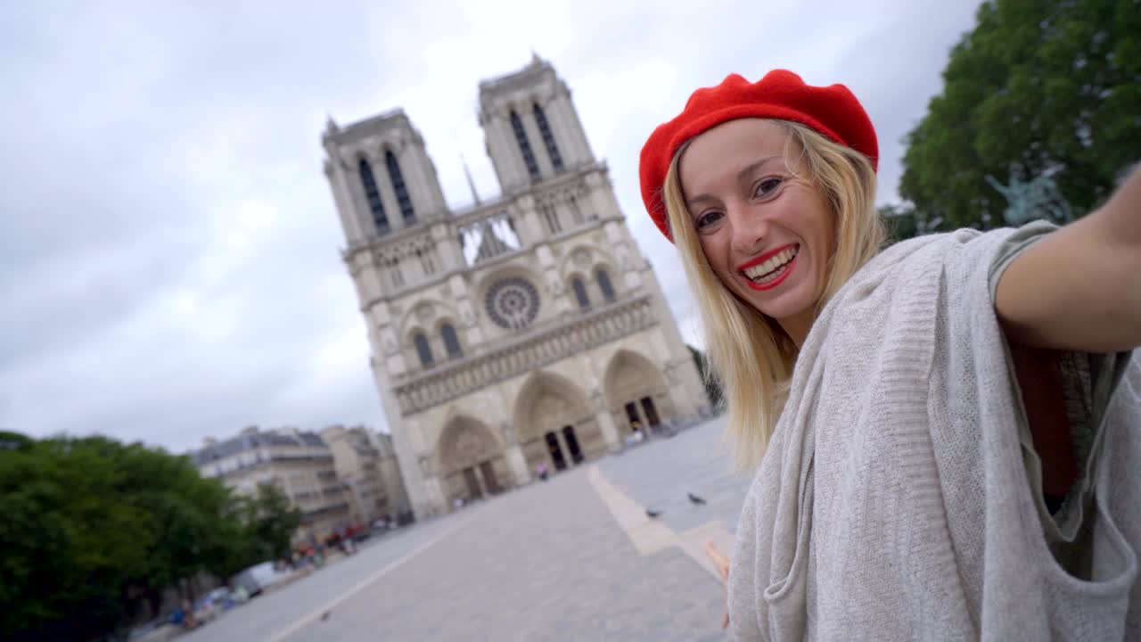 mujer joven de 4k tomando una selfie en parís en la ciudad de notre dame usando un teléfono móvil