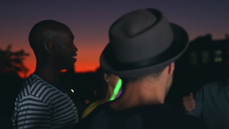 friends dancing with glowsticks at a party on a rooftop