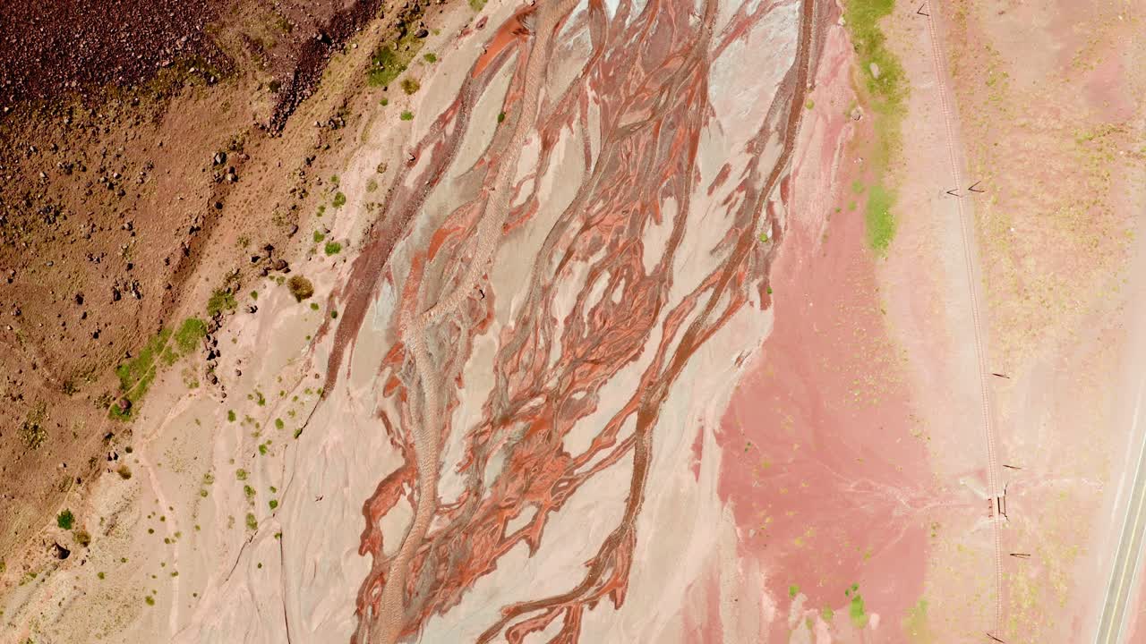 Vista dall'alto di texture minerali colorate e rocce erose modellate da fiumi glaciali intrecciati nel Parco Provinciale dell'Aconcagua, Mendoza, Argentina.