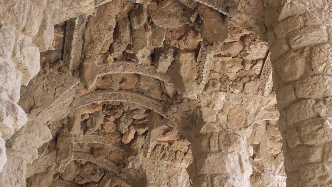 sendero con columnas bajo el viaducto de la calzada con techo de bóveda de piedra en el parque guell en barcelona, cataluña, españa